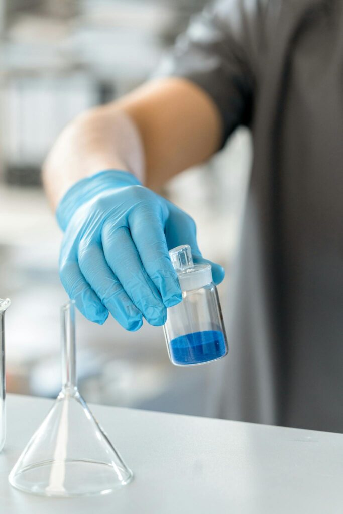 Close-up of a scientist using a lab apparatus to hold a blue solution in a research environment.